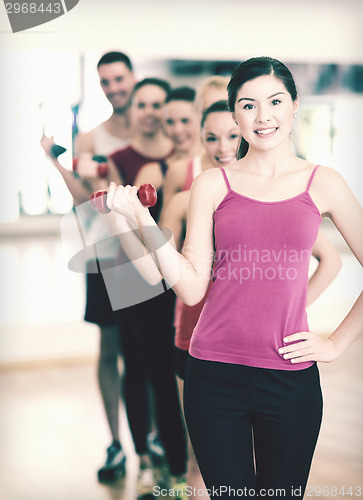 Image of group of smiling people with dumbbells in the gym