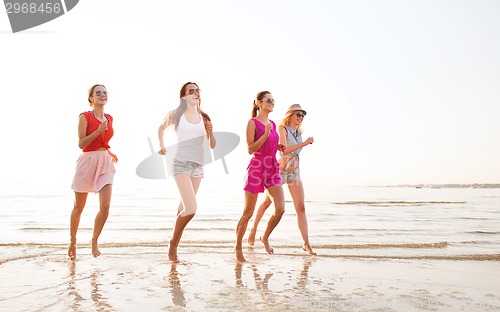 Image of group of smiling women running on beach