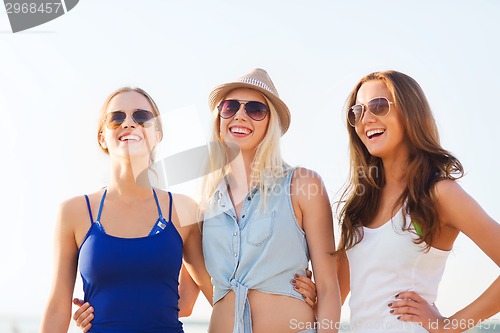 Image of group of smiling women in sunglasses on beach