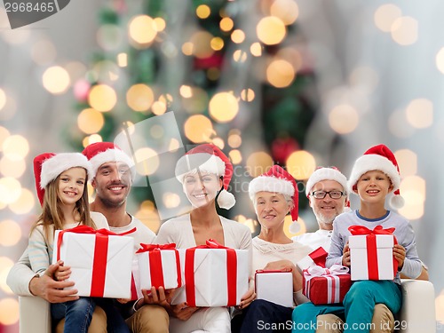 Image of happy family in santa helper hats with gift boxes