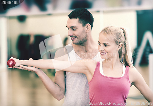 Image of male trainer with woman working out with dumbbell