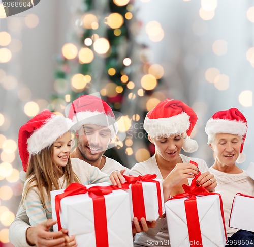 Image of happy family in santa helper hats with gift boxes