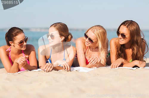 Image of group of smiling women in sunglasses on beach