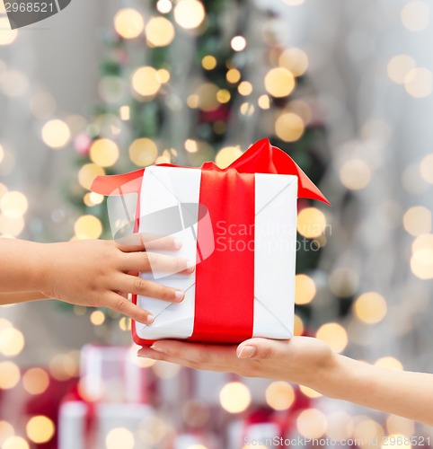 Image of close up of child and mother hands with gift box