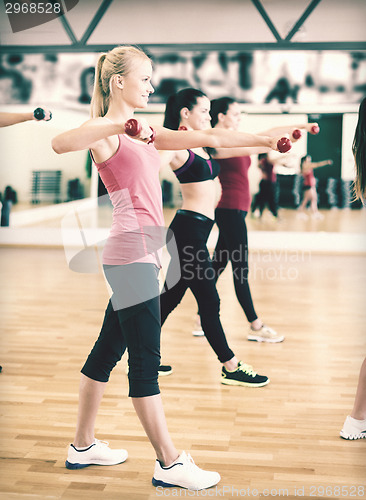 Image of group of smiling people working out with dumbbells
