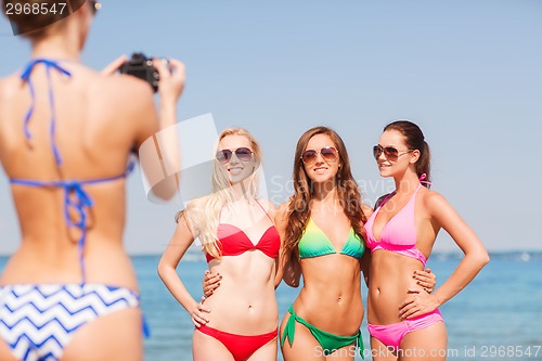 Image of group of smiling women photographing on beach