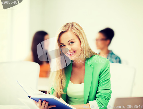 Image of smiling student girl reading book at school