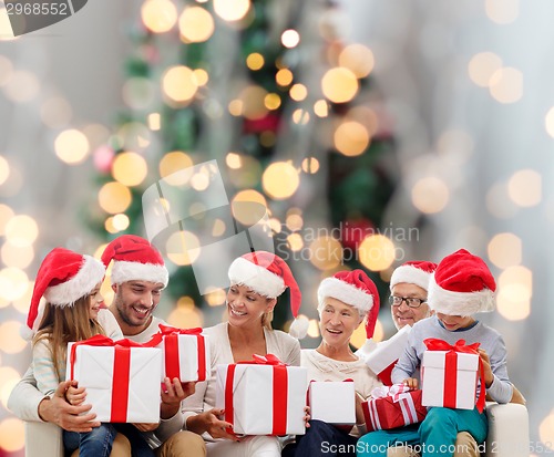 Image of happy family in santa helper hats with gift boxes