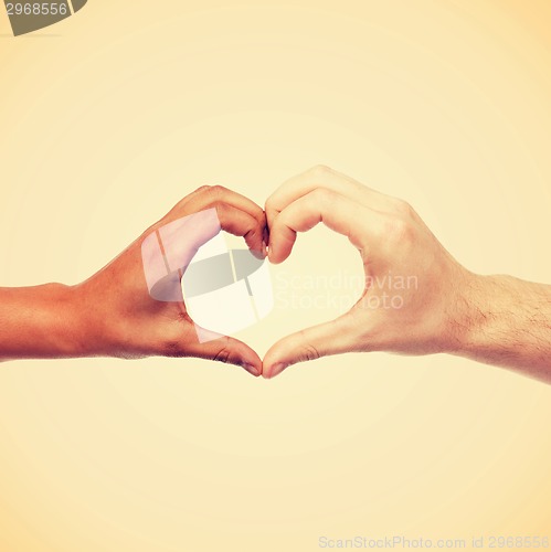 Image of woman and man hands showing heart shape