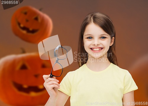 Image of smiling girl in glasses over pumpkins background