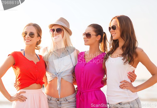 Image of group of smiling women in sunglasses on beach