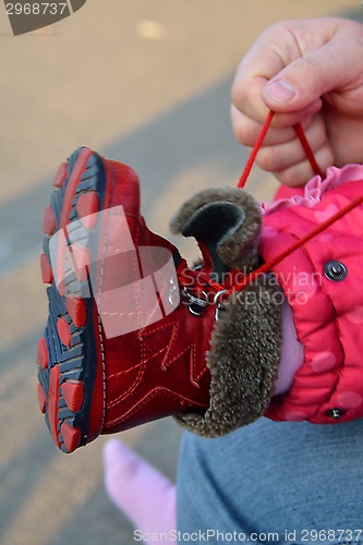 Image of Arms lacing baby girl's shoe