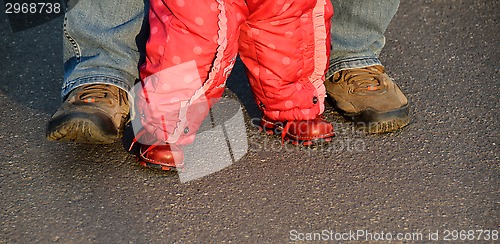 Image of legs of a man helping baby girl to walk