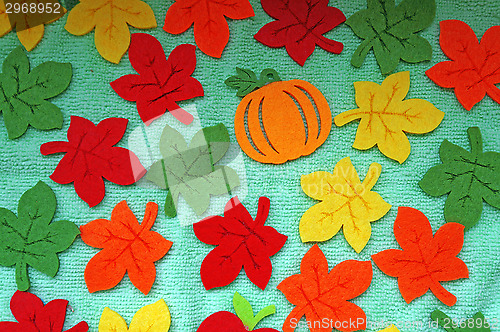 Image of Bright Maple leaves out of felt on a light green fabric as a bac