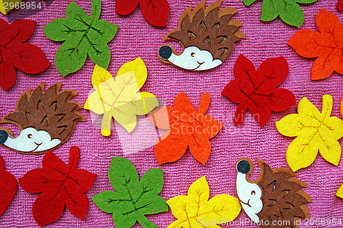 Image of Hedgehogs and colorful Maple leaves out of felt on a pink fabric
