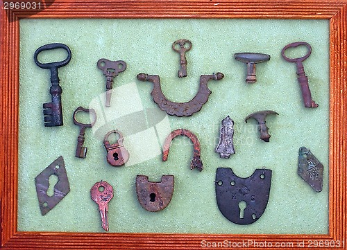 Image of A collection of very old keys and locks in a wooden frame