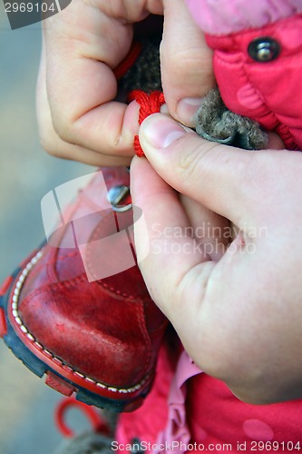 Image of men hands lacing little shoe