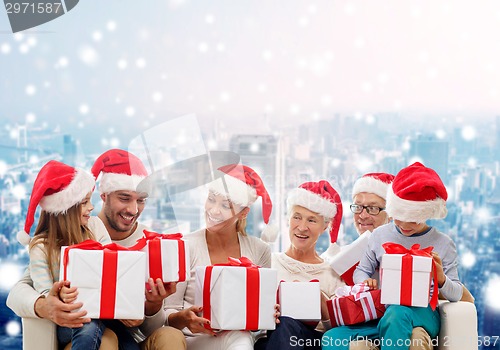 Image of happy family in santa helper hats with gift boxes