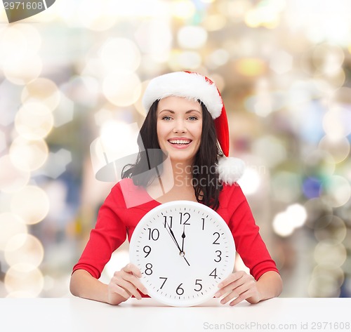 Image of smiling woman in santa helper hat with clock