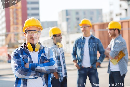 Image of group of smiling builders in hardhats outdoors