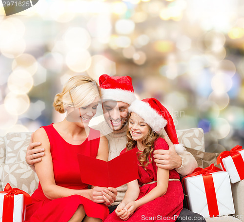 Image of happy family in santa helper hats with gift boxes