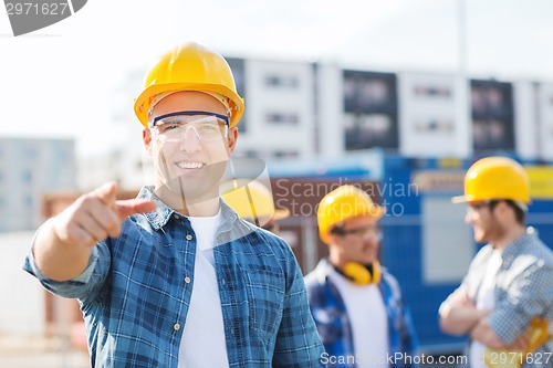 Image of group of smiling builders in hardhats outdoors