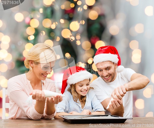 Image of happy family in santa helper hats cooking