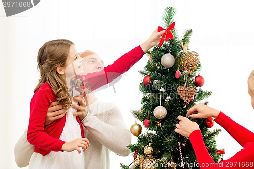 Image of smiling family decorating christmas tree at home