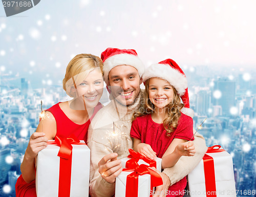 Image of happy family in santa helper hats with gift boxes