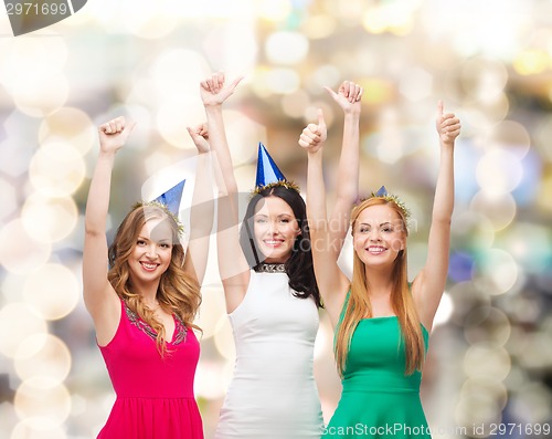 Image of smiling women in party caps showing thumbs up