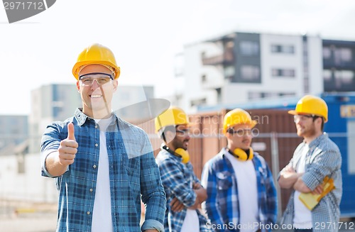 Image of group of smiling builders in hardhats outdoors