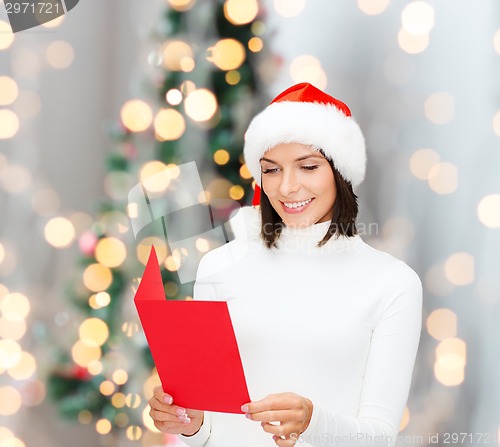 Image of smiling woman in santa hat with greeting card