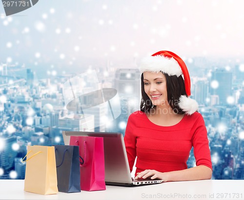 Image of smiling woman in santa hat with bags and laptop