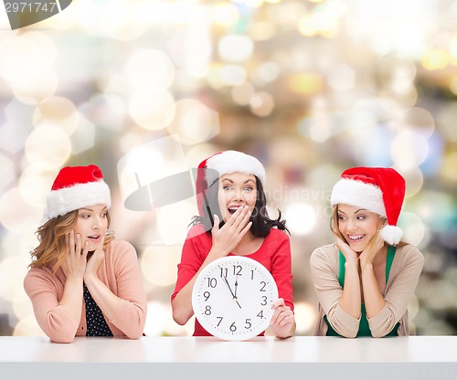 Image of smiling women in santa helper hats with clock