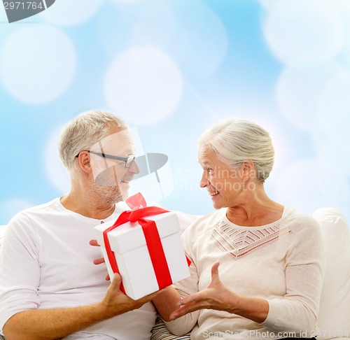 Image of happy senior couple with gift box at home