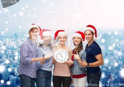 Image of group of teenagers in santa helper hats with clock