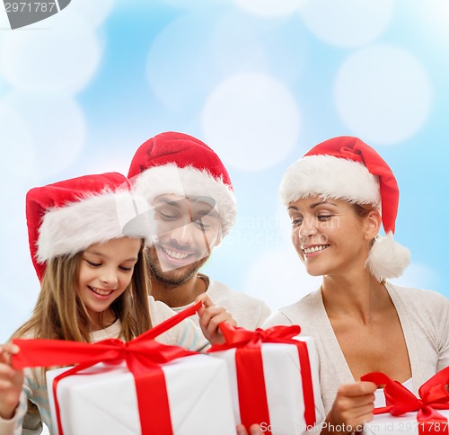 Image of happy family in santa helper hats with gift boxes