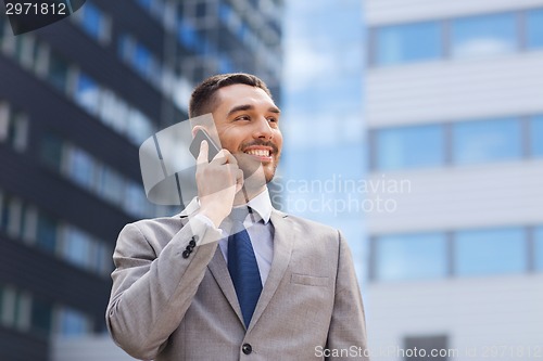 Image of smiling businessman with smartphone outdoors