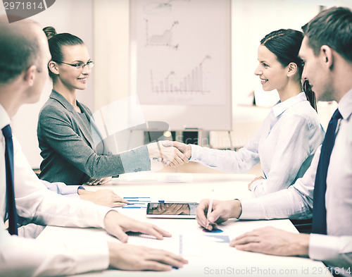 Image of two businesswomen shaking hands in office