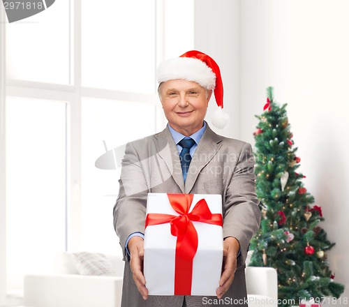 Image of smiling man in suit and santa helper hat with gift