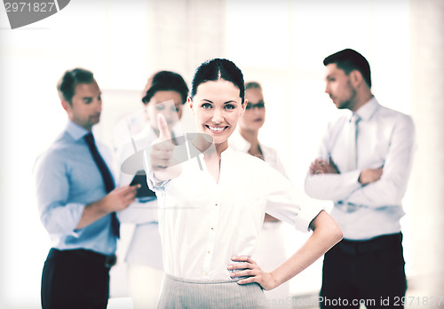 Image of businesswoman in office showing thumbs up