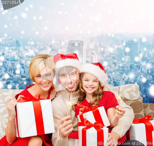 Image of happy family in santa helper hats with gift boxes