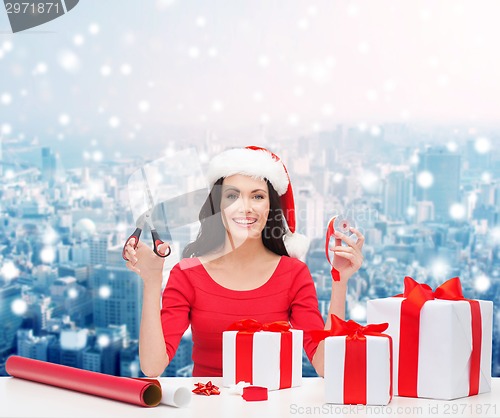 Image of smiling woman in santa helper hat packing gifts