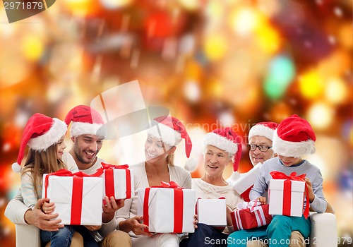 Image of happy family in santa helper hats with gift boxes