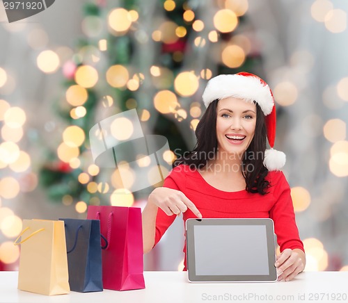 Image of smiling woman in santa hat with bags and tablet pc