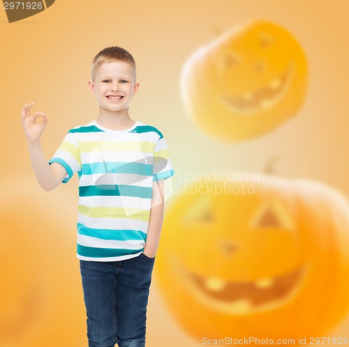 Image of smiling boy over pumpkins background