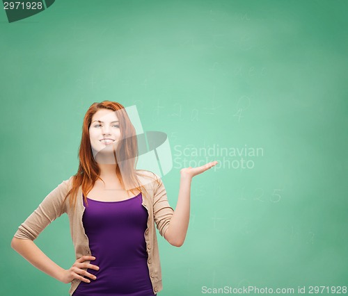 Image of smiling teenage girl holding something on her palm