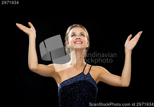 Image of smiling woman raising hands and looking up