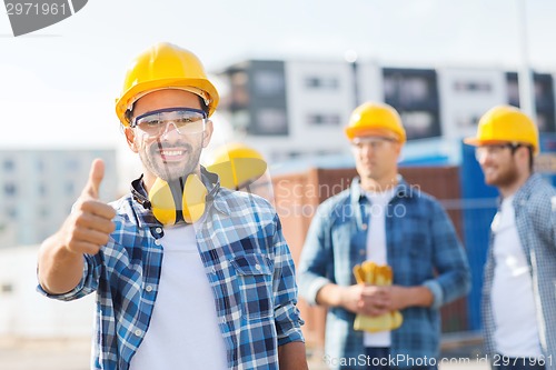 Image of group of smiling builders in hardhats outdoors