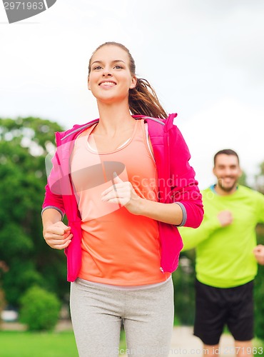 Image of smiling couple running outdoors